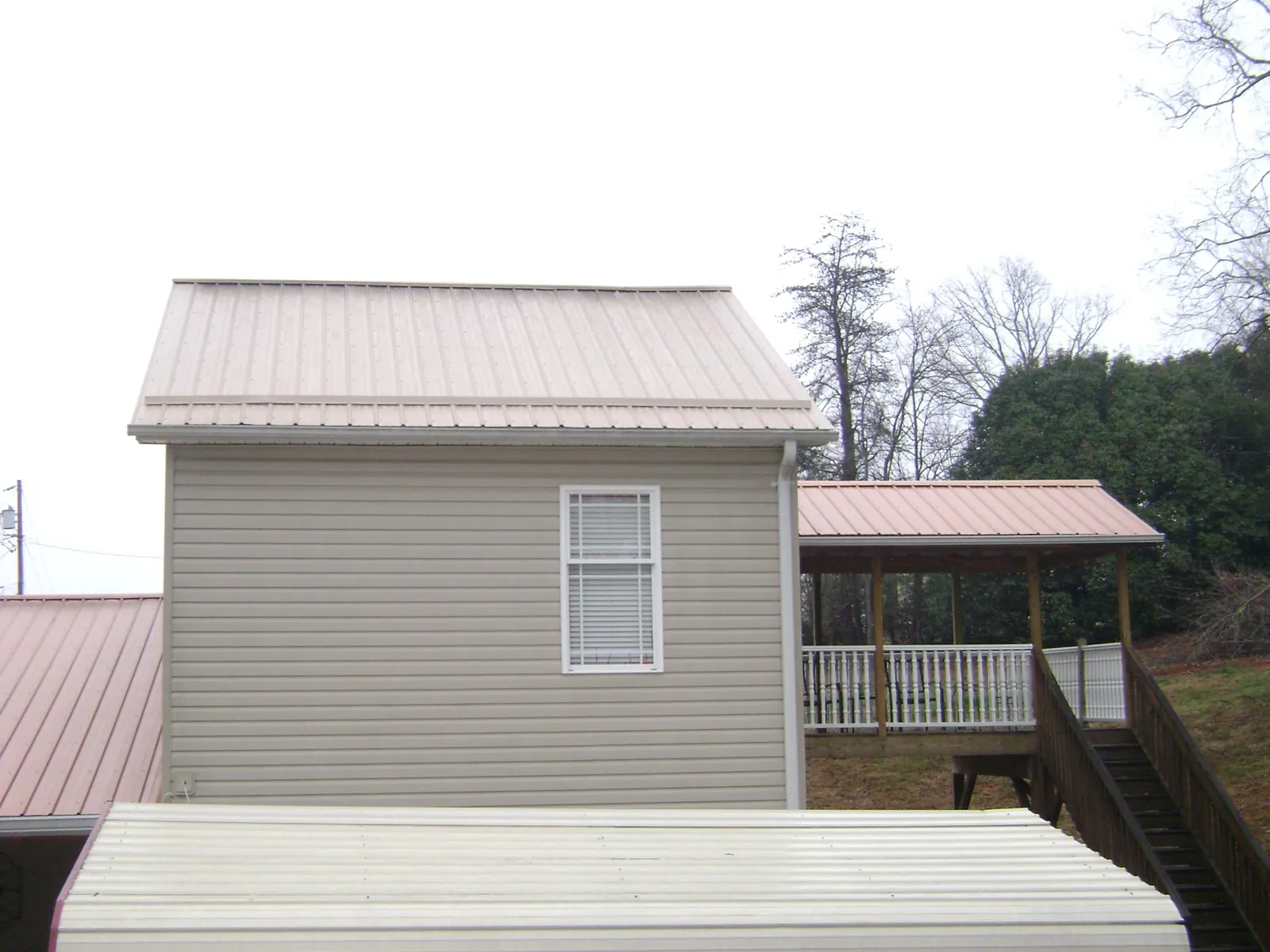 Tan metal roofs on a two story addition and attached porch, from a Roof Replacement job in Racine